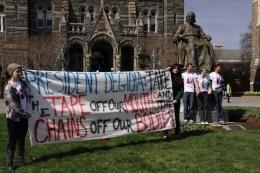 Plan A members stood chained to the statue of John Carroll as other members of the group held a banner protesting Georgetown's approach to reproductive rights.