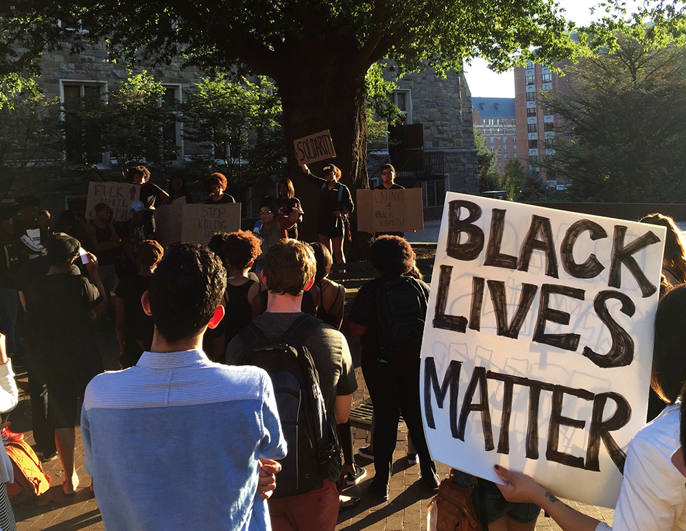 DANIEL SMITH/THE HOYA Students and faculty gathered in Red Square on Friday to rally against the police brutality that led to the shootings of Terrence Crutcher and Keith Lamont Scott, ending by joining arms to sing "We Shall Overcome."